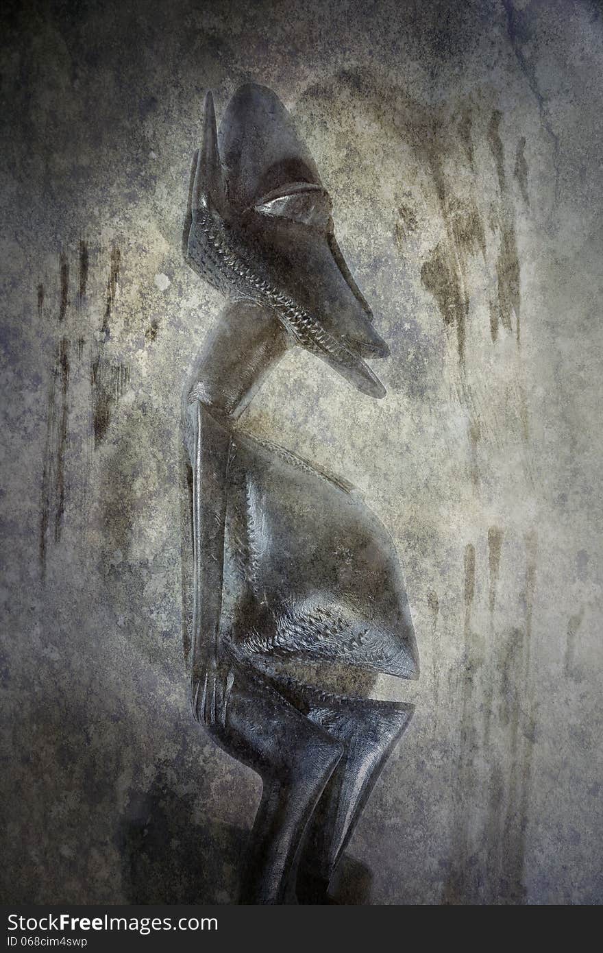 African carved figure idol against a grunge textured background of primitive, ghostly cave painting hand prints. African carved figure idol against a grunge textured background of primitive, ghostly cave painting hand prints.