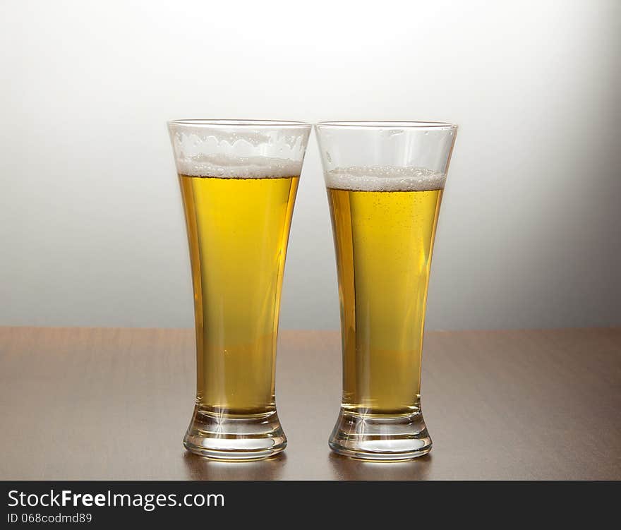 Two mugs of tasty fresh beer on a gray background