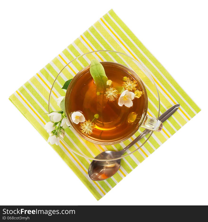 Flower tea in a cup with a saucer, a spoon, a napkin isolated on white. Flower tea in a cup with a saucer, a spoon, a napkin isolated on white