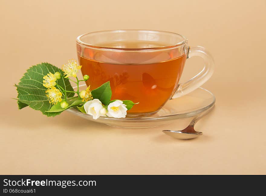 Cup of tea, linden and jasmine flowers, on a beige background