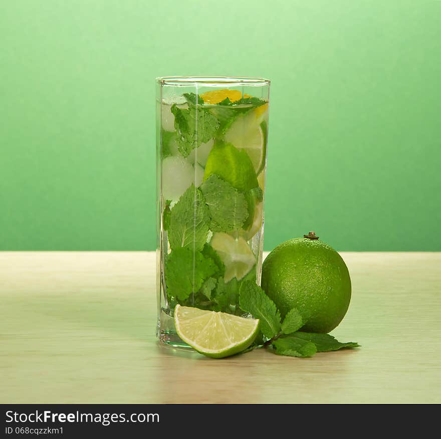 Glass of a mojito, spearmint leaf and juicy lime on a table