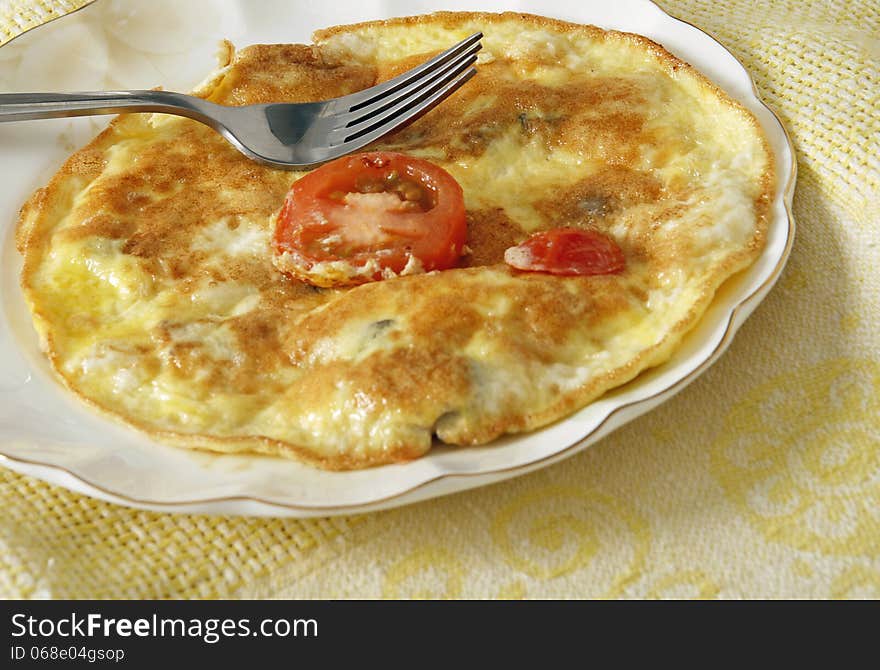 Fried egg omlet with tomato in a plate.