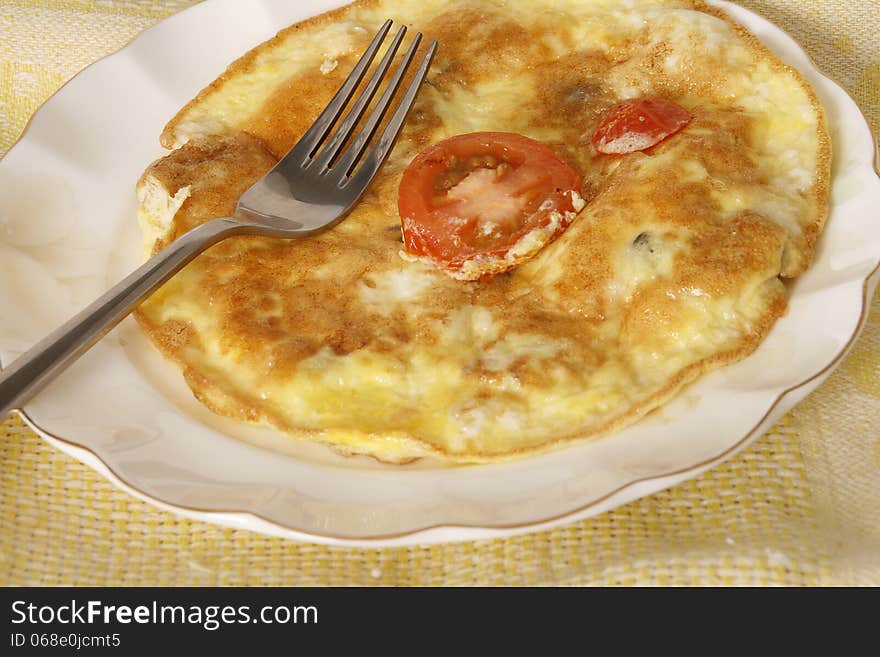 Fried egg omlet with tomato in a plate.