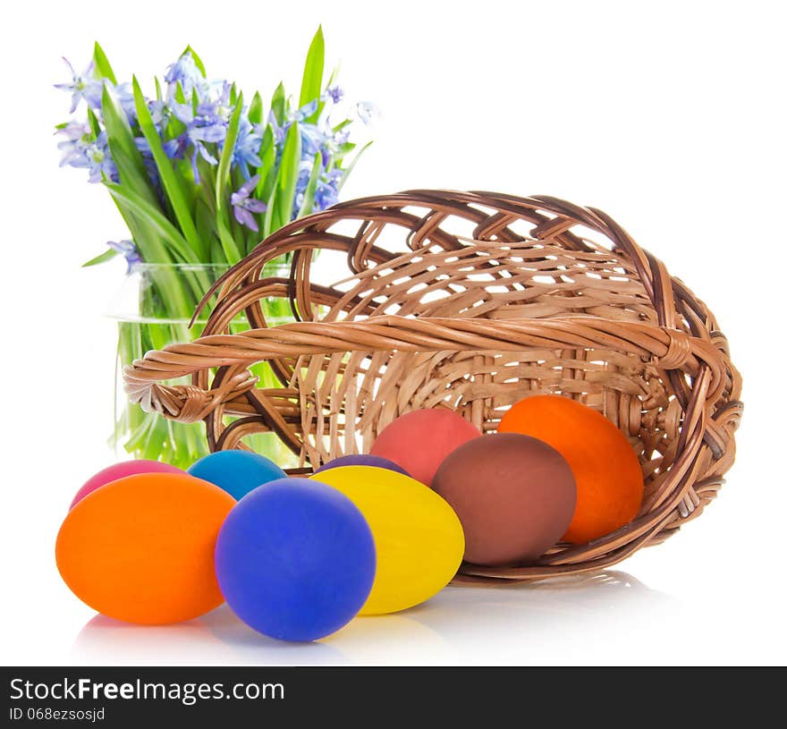 Bright eggs before a basket and flowers in a vase, isolated on white