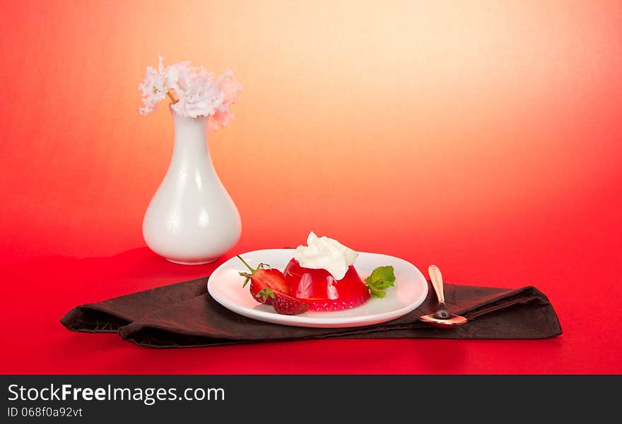 Plate with jelly and whipped cream, a spoon and a brown napkin on the pink