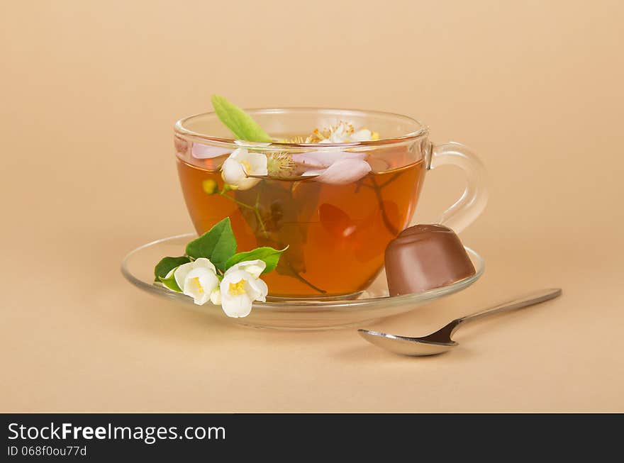 Cup of flower tea and the chocolate, on a beige background