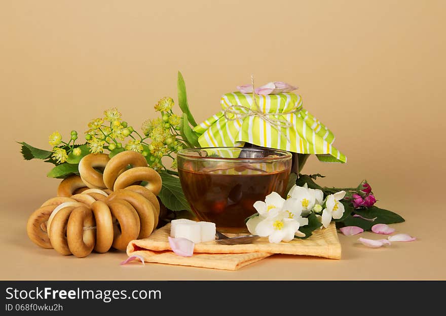 Cup of tea, bagels, sugar, a linden a jasmine and a napkin on the beige. Cup of tea, bagels, sugar, a linden a jasmine and a napkin on the beige