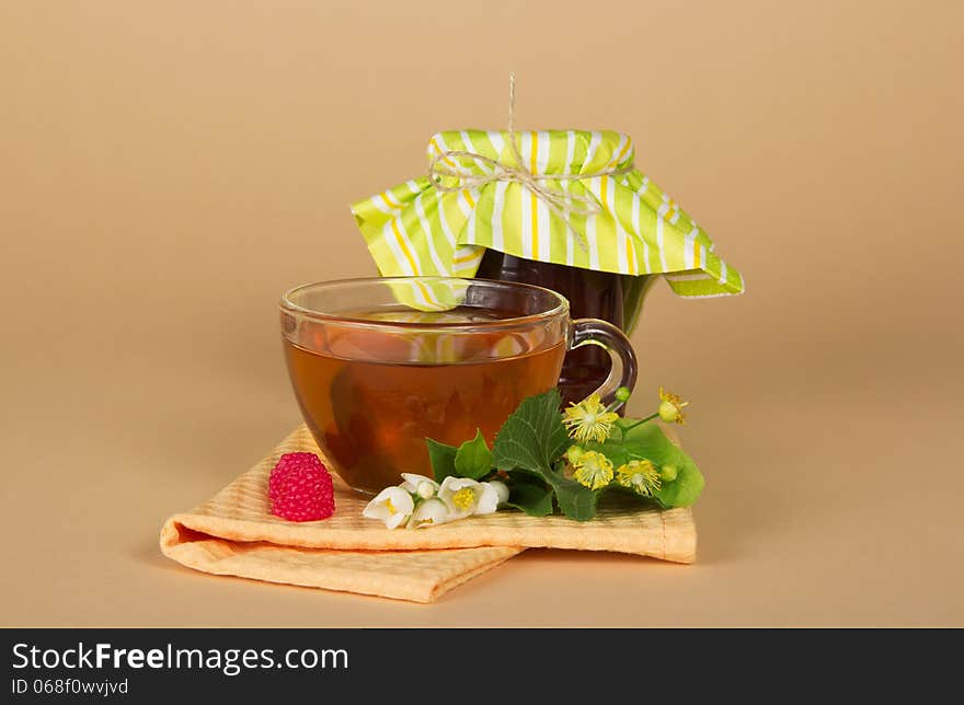 Raspberry jam, tea, flowers, napkin on a beige background