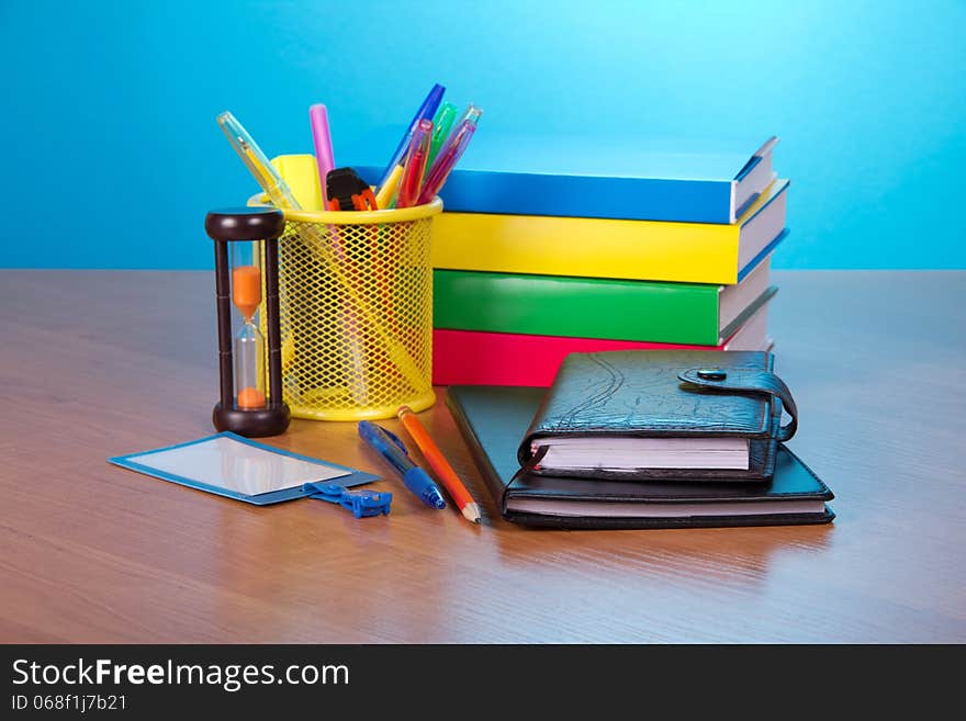 Organizer, notepad, books, blank badge, pens in a support, and hourglasses on a table. Organizer, notepad, books, blank badge, pens in a support, and hourglasses on a table