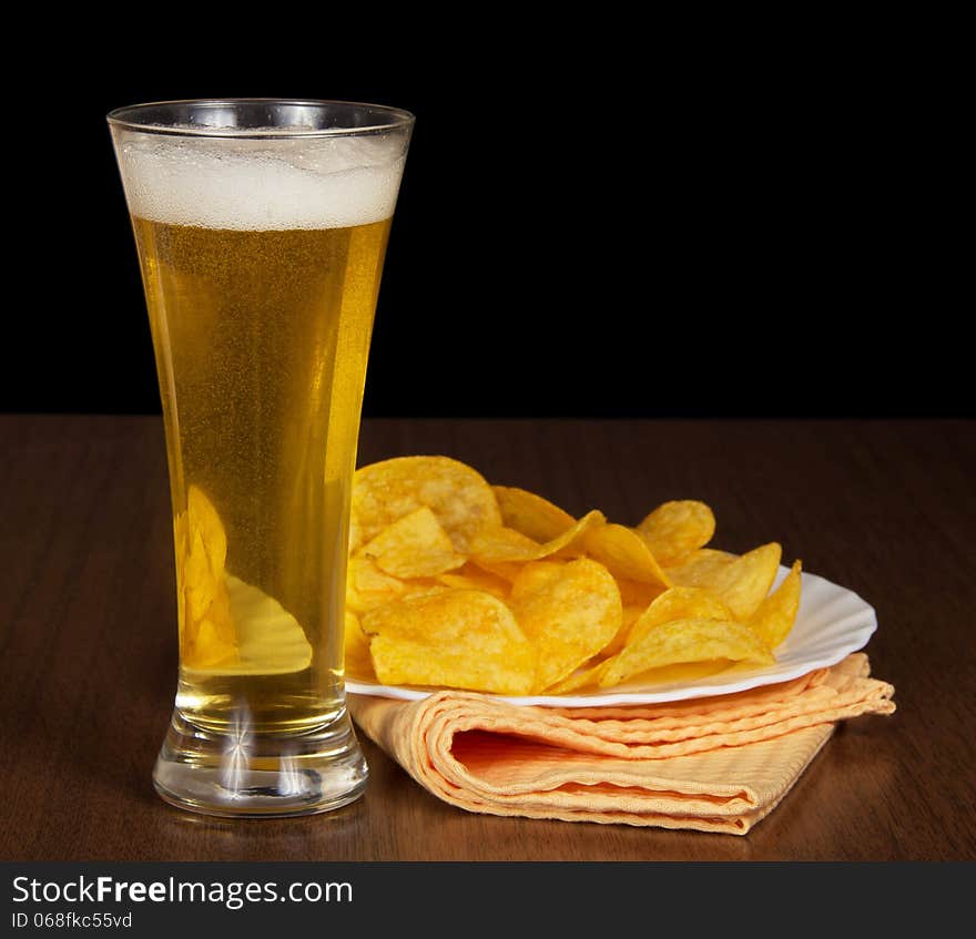 Mug with beer, a dish with chips and a napkin on a table. Mug with beer, a dish with chips and a napkin on a table