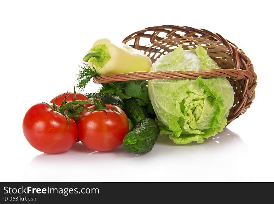 The cabbage, cucumbers, tomatoes and greens, dropped out of a basket, isolated on white. The cabbage, cucumbers, tomatoes and greens, dropped out of a basket, isolated on white