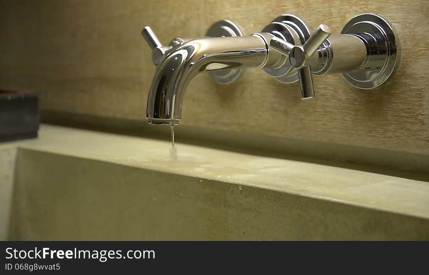 Hand close a dripping water tap faucet in the bathroom