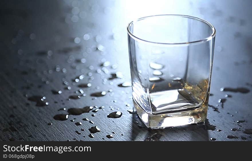 Pouring drinking water into glass on the table with splashed drop on the table