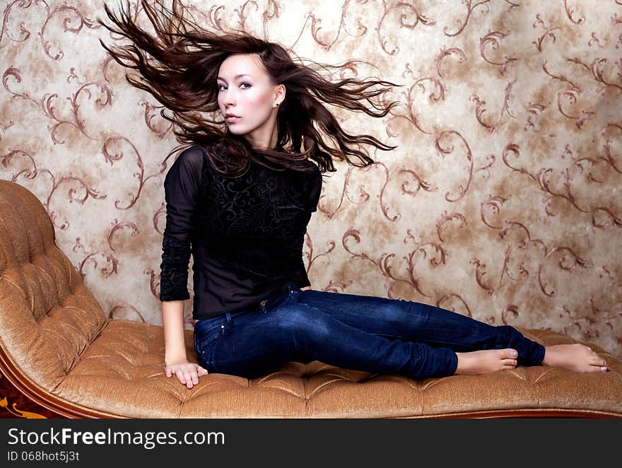 Beautiful girl waving her brown hair on vintage couch