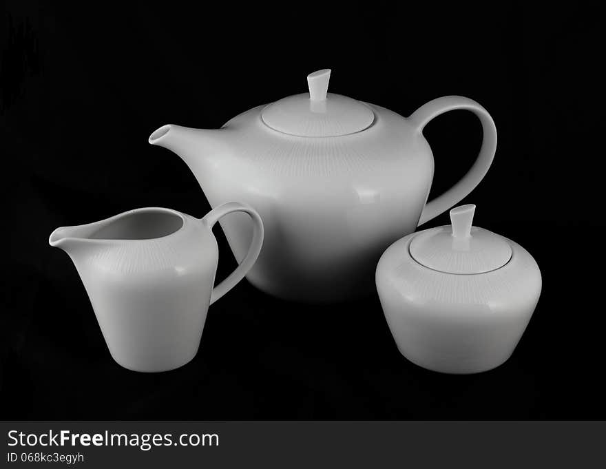 Set of white porcelain jugs and sugar bowl on a black background. Set of white porcelain jugs and sugar bowl on a black background