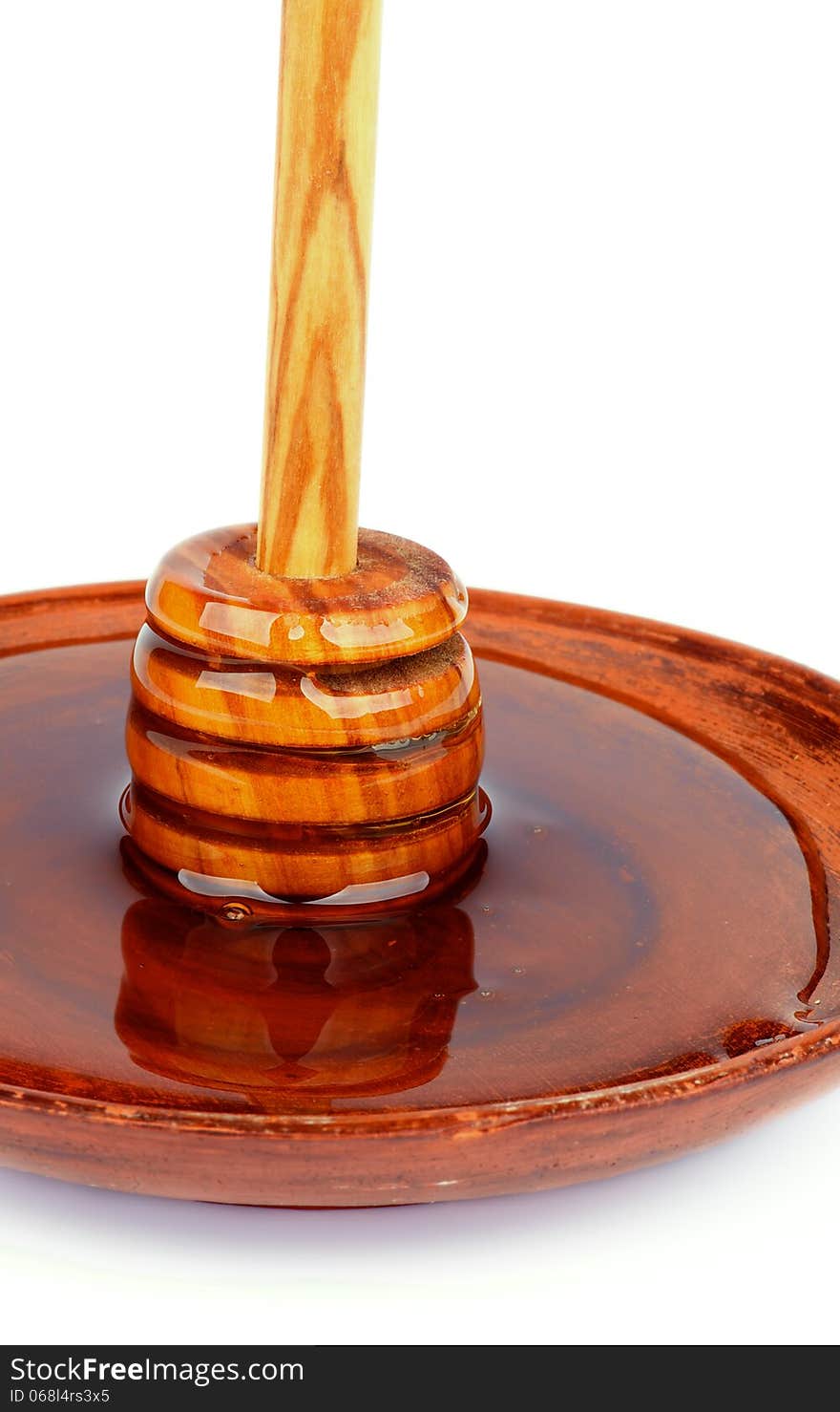 Wooden Dipper with Honey Standing into Brown Plate isolated on white background. Wooden Dipper with Honey Standing into Brown Plate isolated on white background