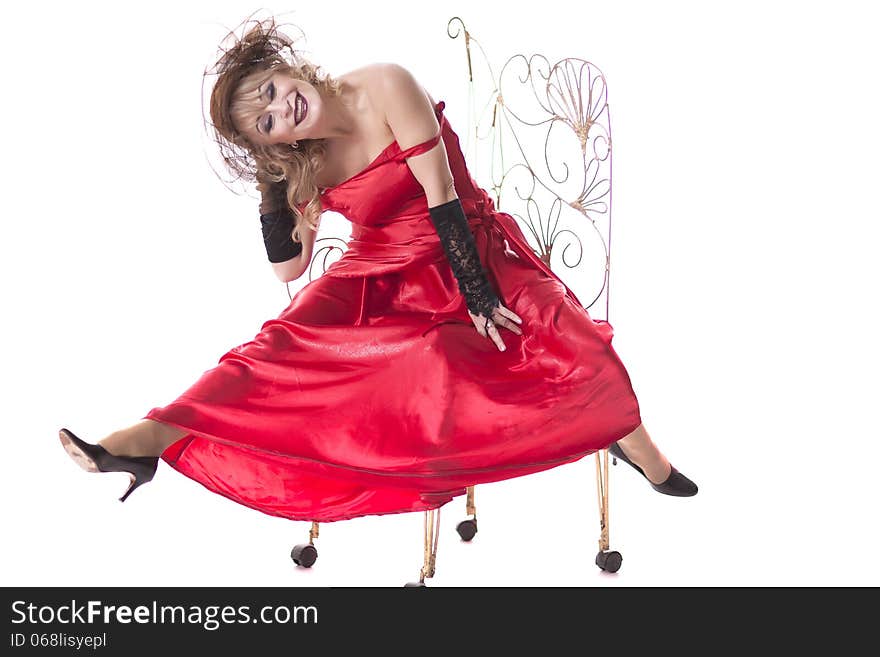 Woman in a red dress posing on a chair on a white background