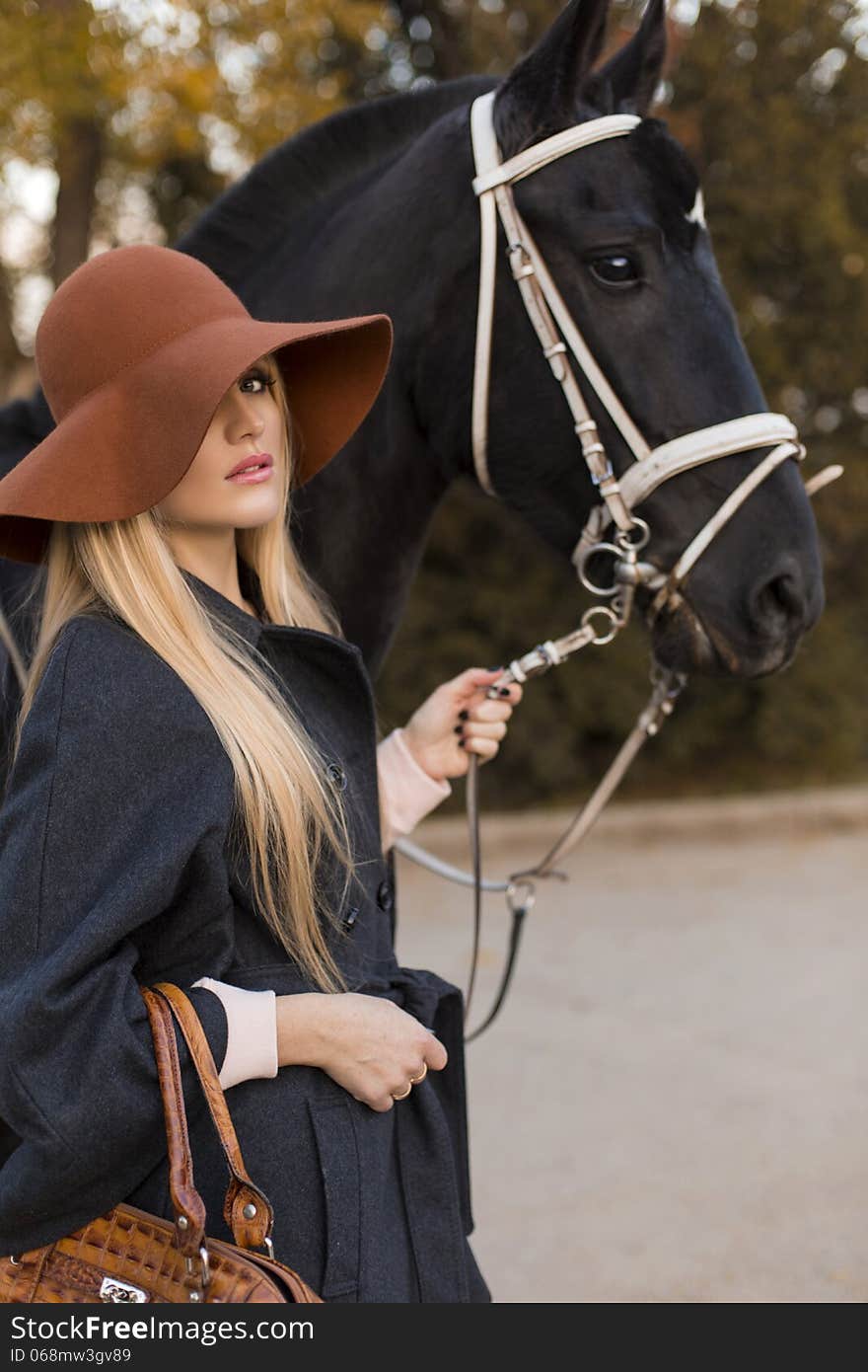 Beautiful girl with blond hair and black horse. Beautiful girl with blond hair and black horse