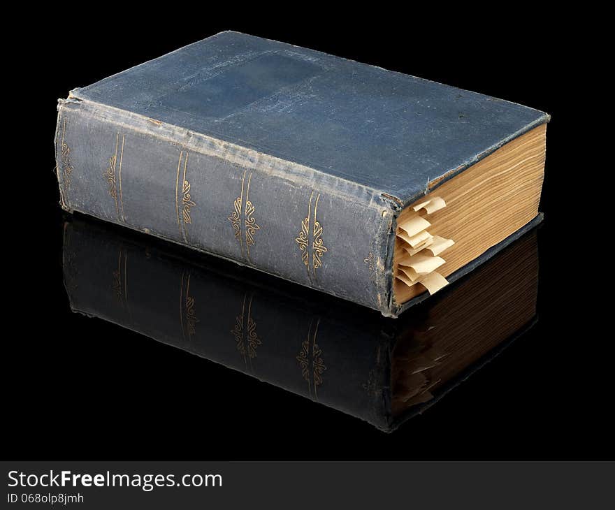 The closed ancient book in dark blue cover on a black background