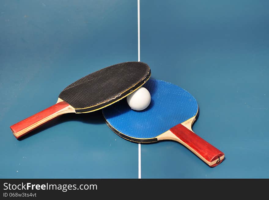 Blue and Black Table Tennis paddles and ball on table tennis table. Blue and Black Table Tennis paddles and ball on table tennis table