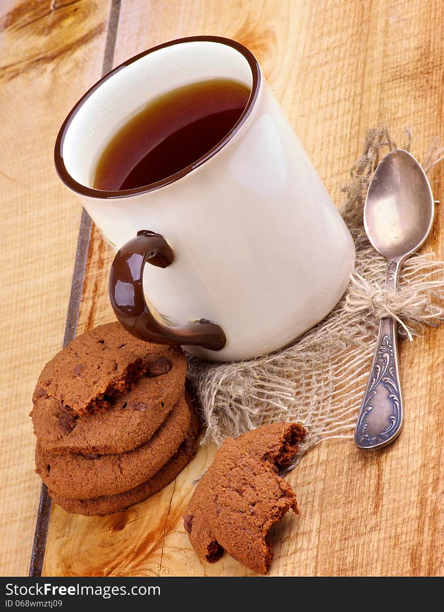 Rustic Cup of Black Tea with Chocolate Chip Cookies and Tea Spoon closeup on Wooden background. Rustic Cup of Black Tea with Chocolate Chip Cookies and Tea Spoon closeup on Wooden background