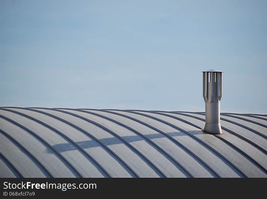 A modern chimney on top of a recent building with its shadow