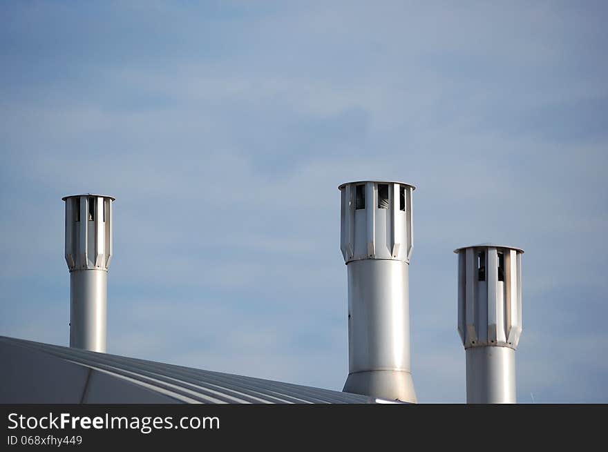 Some modern chimneys on top of a recent building