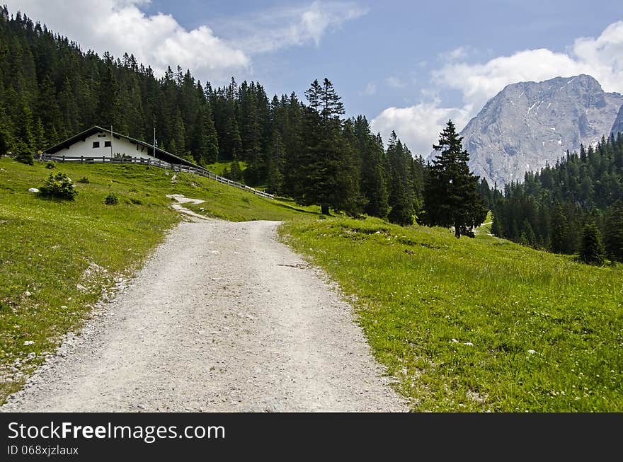 Hiking path in the Austrians alps with blue sky beautiful landscape and house on the way.