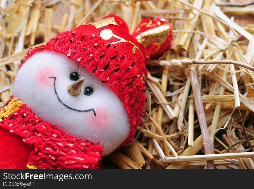 Red dressed puppet snowman over straw. Red dressed puppet snowman over straw