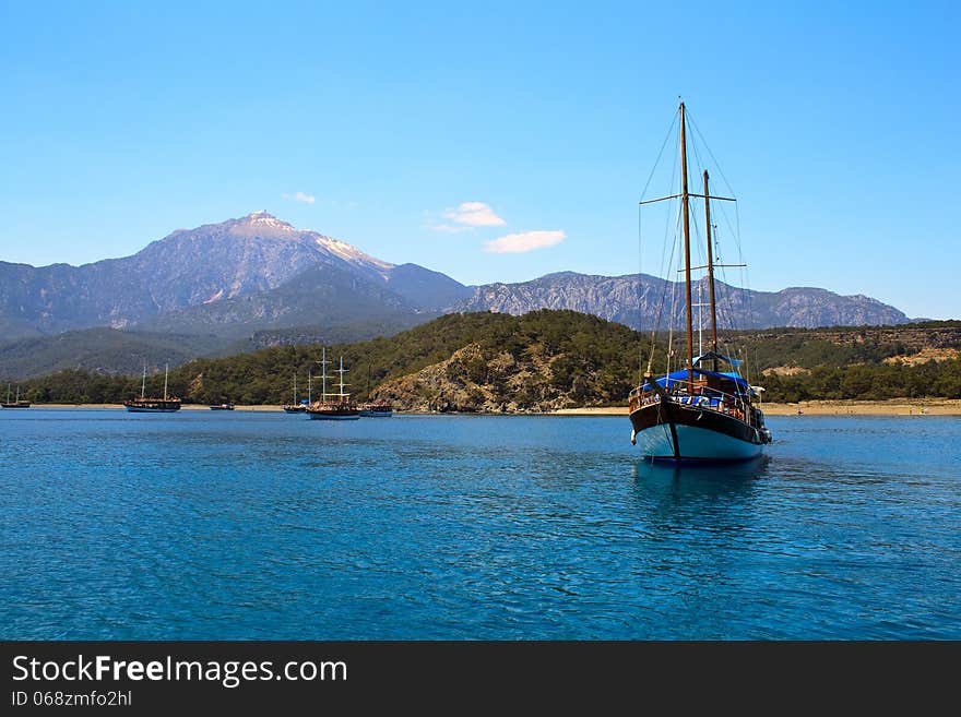 Sailing yacht sail through the sea on the background of mountains