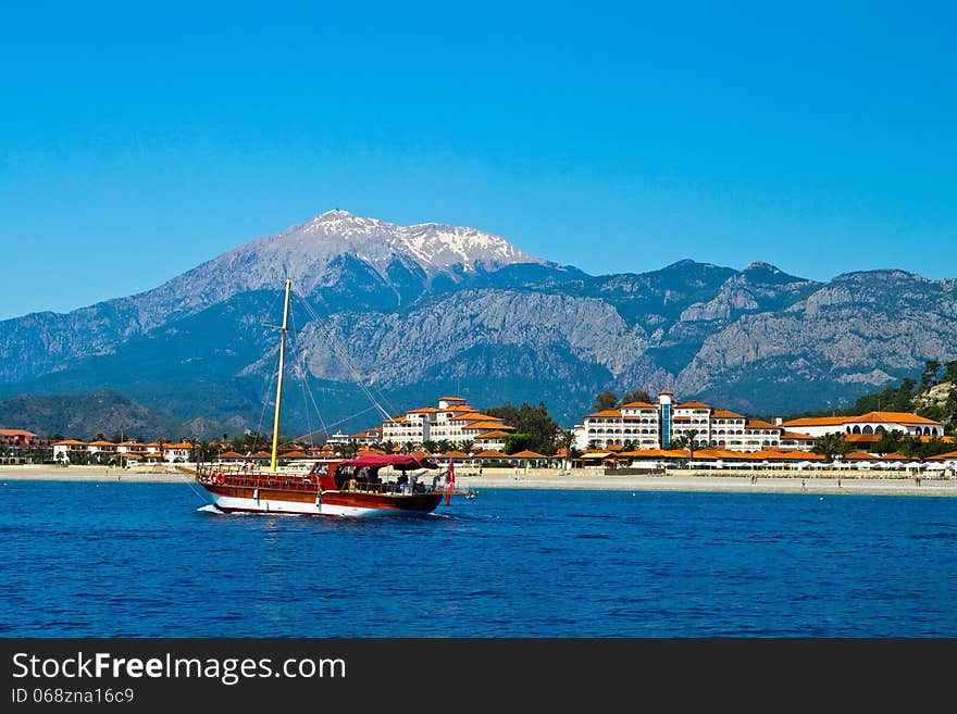 Sailing yacht sail through the sea on the background of mountains