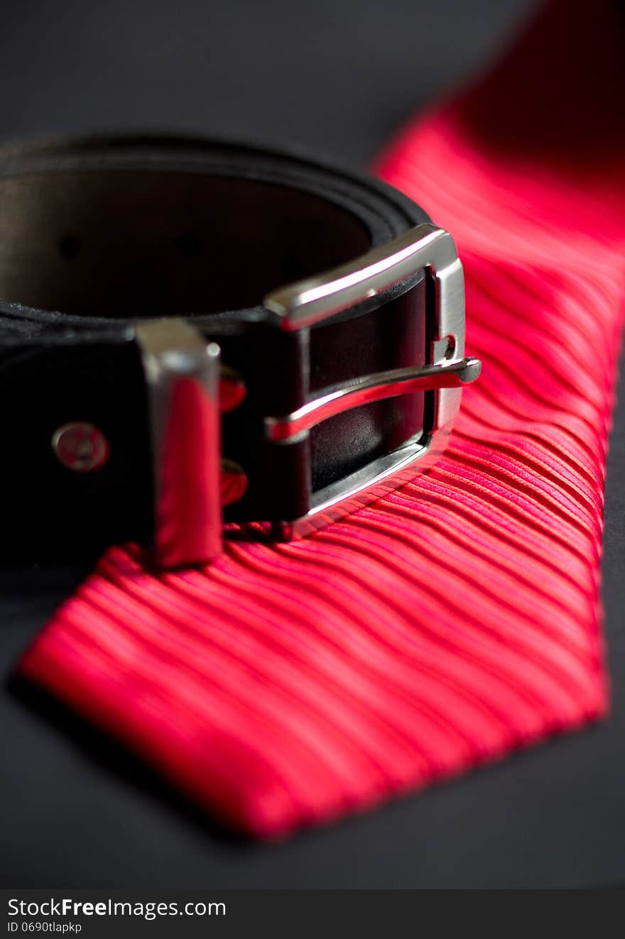 Red necktie and leather belt. Red necktie and leather belt