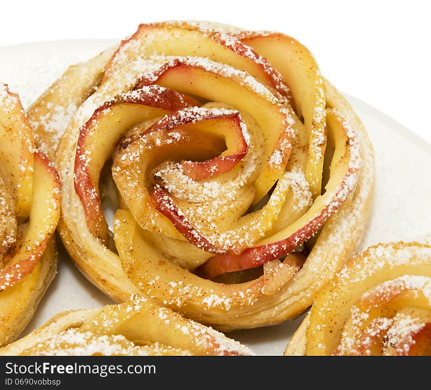 Sweet rolls with apples in the form of roses on plate on white isolated background. Sweet rolls with apples in the form of roses on plate on white isolated background