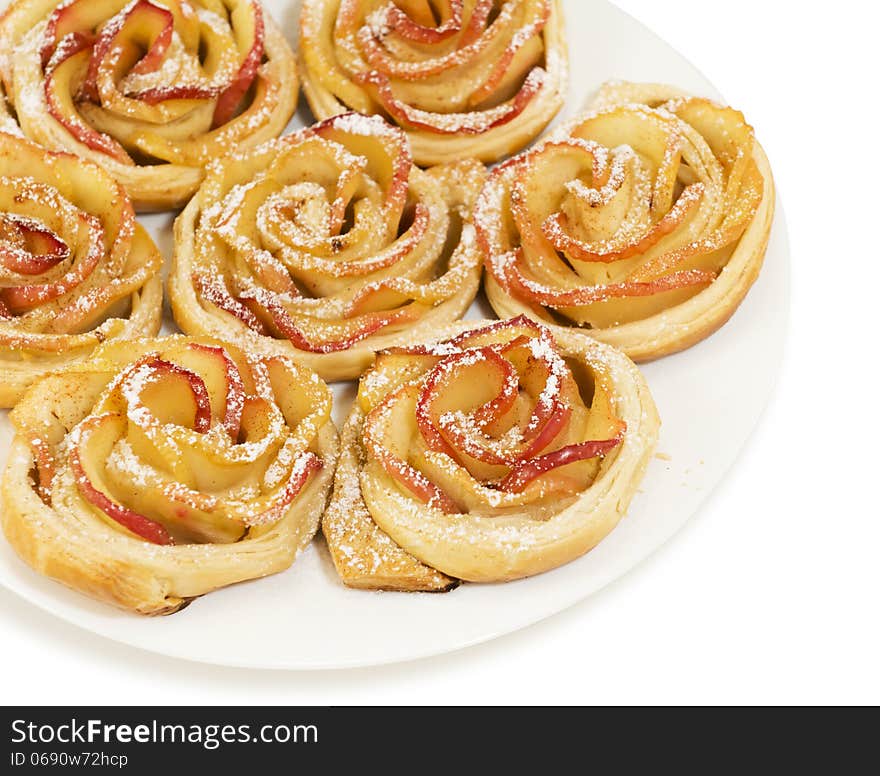 Sweet rolls with apples in the form of roses on plate on white isolated background. Sweet rolls with apples in the form of roses on plate on white isolated background