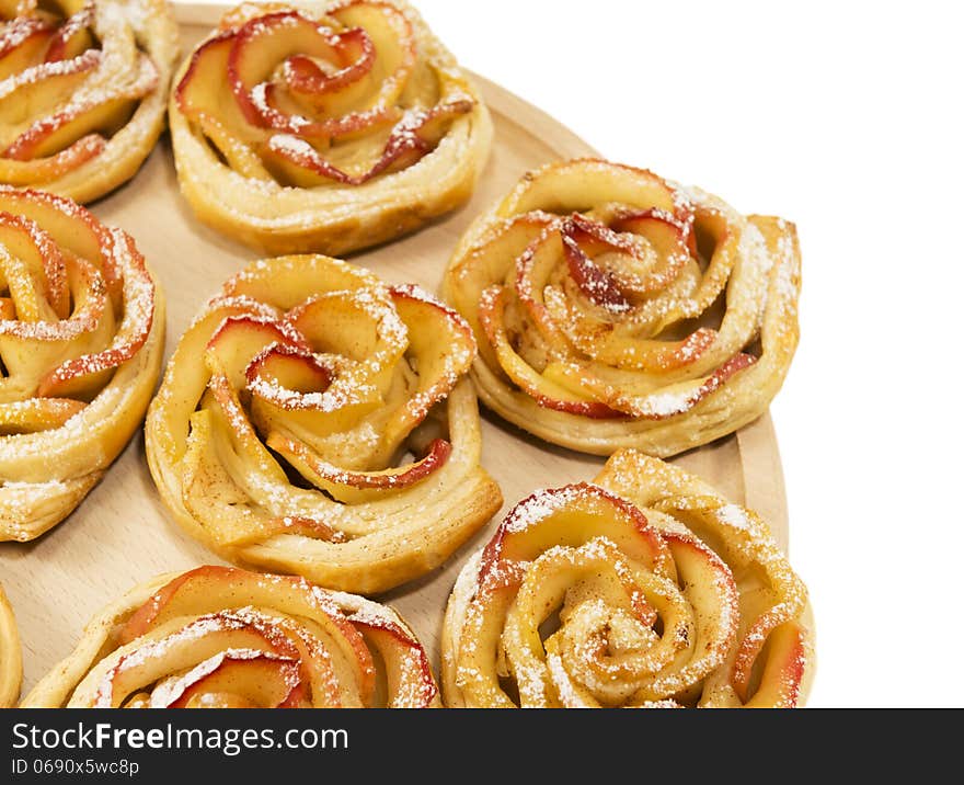 Sweet rolls with apples in the form of roses on wooden board on