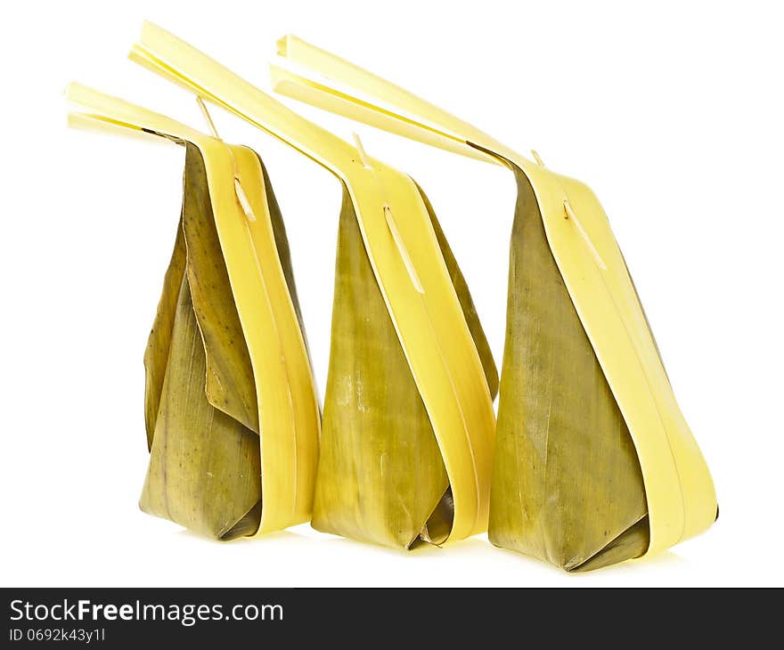 Arrange of three banana leaves package with long coconut leaves tail of Thai dessert on white background. Arrange of three banana leaves package with long coconut leaves tail of Thai dessert on white background