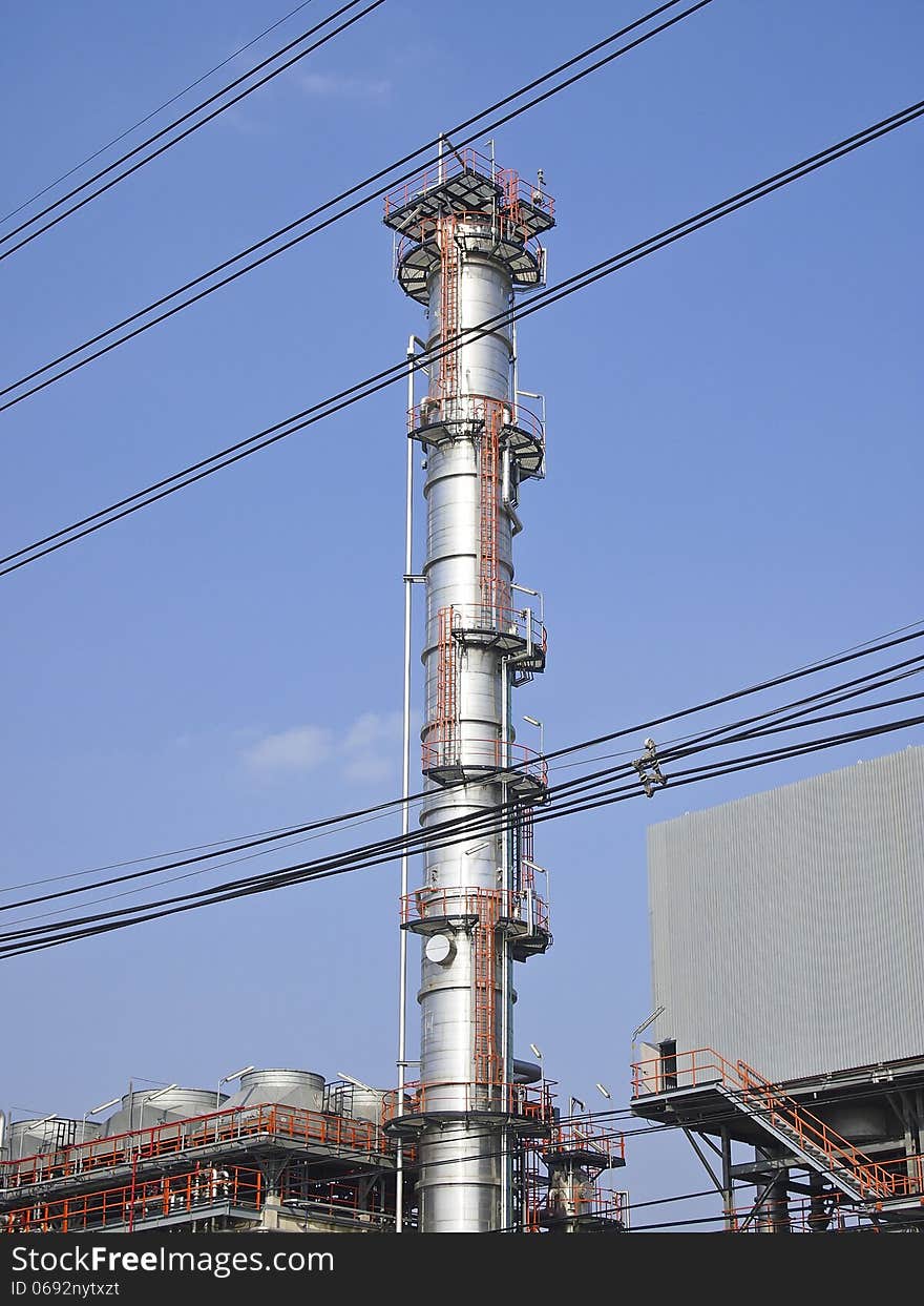 High distillation tower behind cable line in sunny day. High distillation tower behind cable line in sunny day