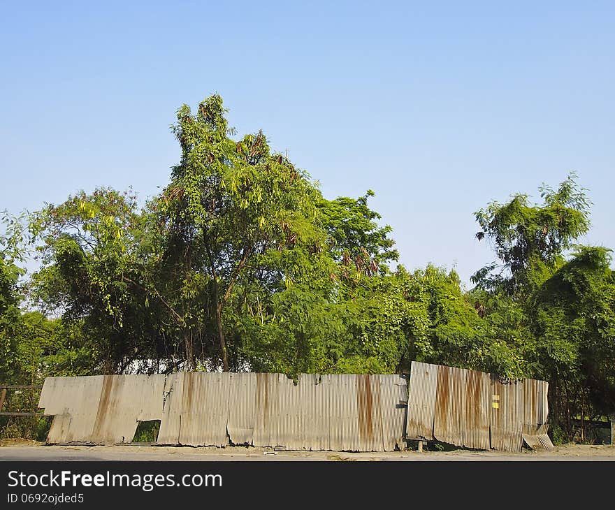 Old fence at side of secluded road in sunny day. Old fence at side of secluded road in sunny day