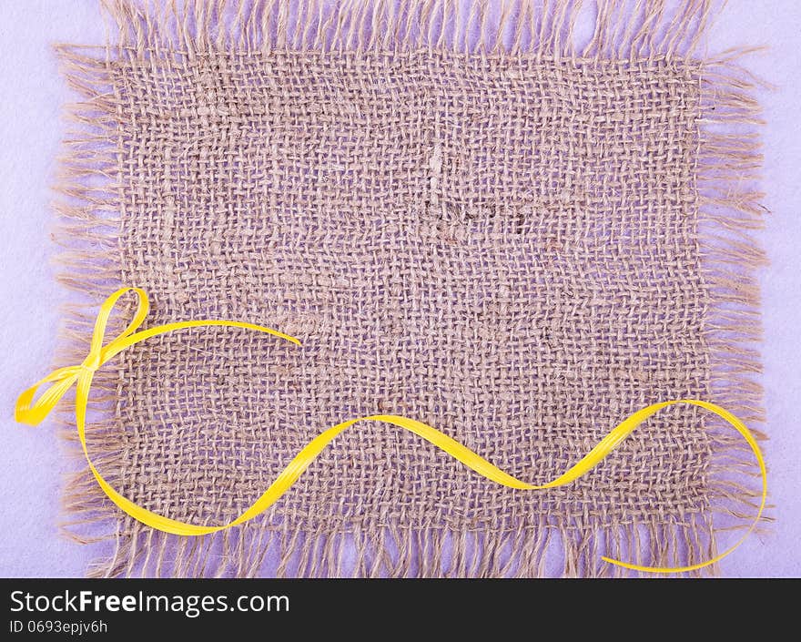 Burlap patch over lilac felt backdrop with yellow ribbon. Burlap patch over lilac felt backdrop with yellow ribbon