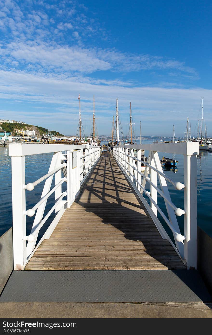 White wooden jetty walkway to marina with blue sky and clouds