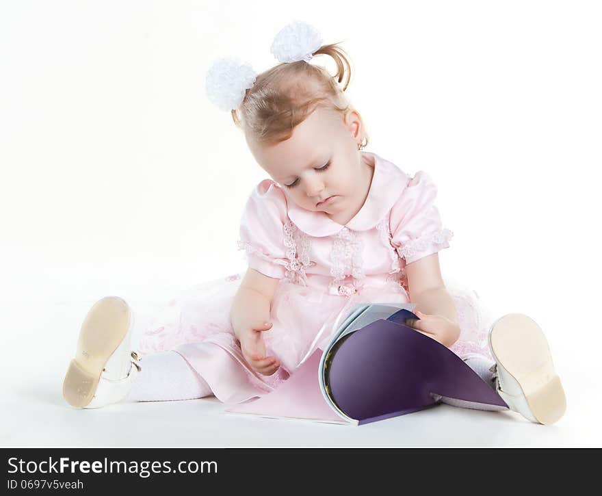 Little girl sitting on the floor and flipping magazine