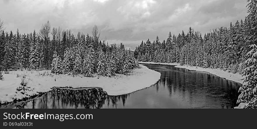 This black and white image of the stream with snow covered trees on both sides was taken in Glacier National Park, Montana. This black and white image of the stream with snow covered trees on both sides was taken in Glacier National Park, Montana.