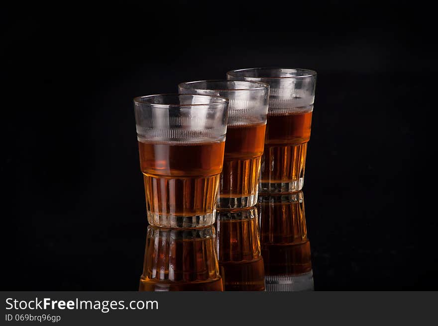 Three shot glasses full of dark colored alcohol on top of a bar table. Three shot glasses full of dark colored alcohol on top of a bar table.