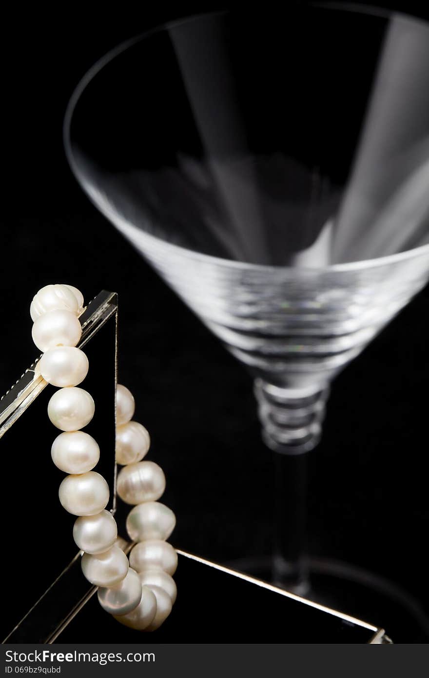 Pearl bracelet hanging on an open jewelry box on a black background