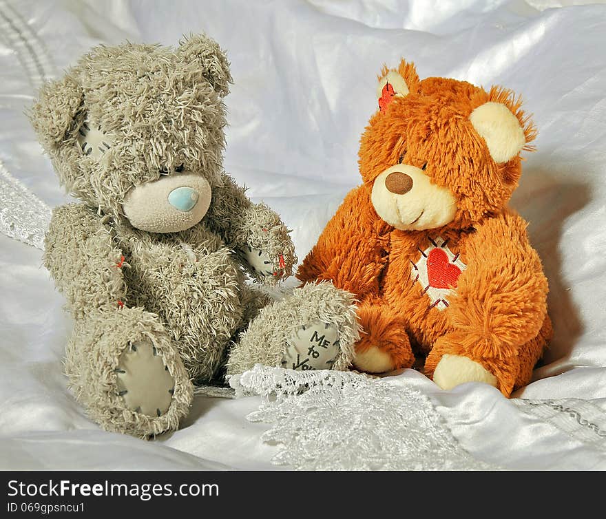 Toys gray and brown bears on the beautiful white linen in the bedroom. Toys gray and brown bears on the beautiful white linen in the bedroom