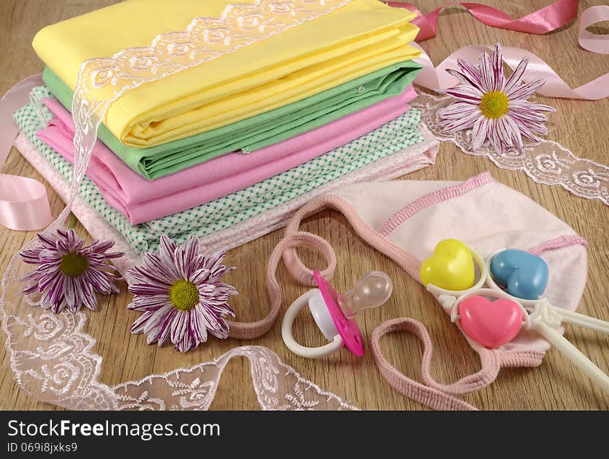 Baby still life of baby linen and small hat with flowers and playthings. Baby still life of baby linen and small hat with flowers and playthings