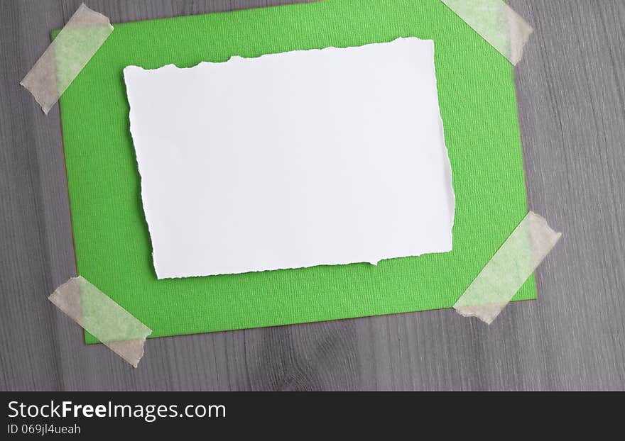 A white paper on a canvas textured paper taped on a black and white wood background. A white paper on a canvas textured paper taped on a black and white wood background