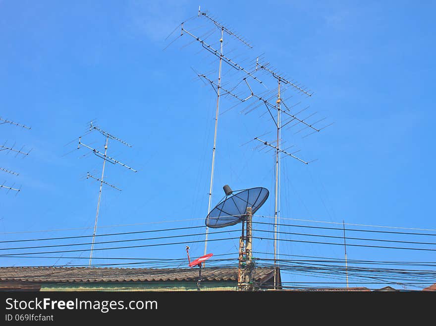 Satellite dish and Television antenna on roof with blue sky