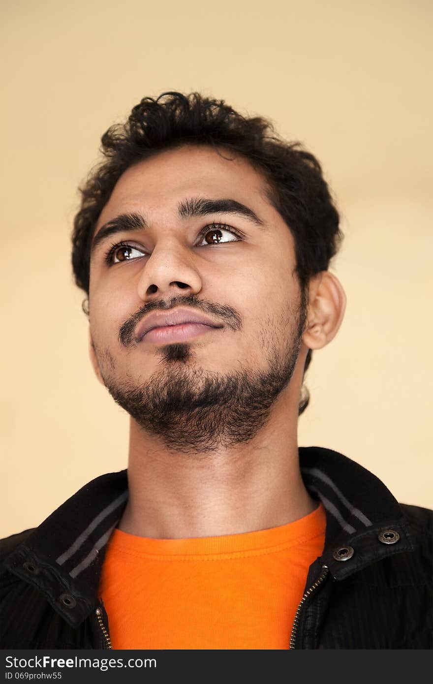 Indian young handsome man in thinking posture with black jacket and orange t-shirt. Indian young handsome man in thinking posture with black jacket and orange t-shirt