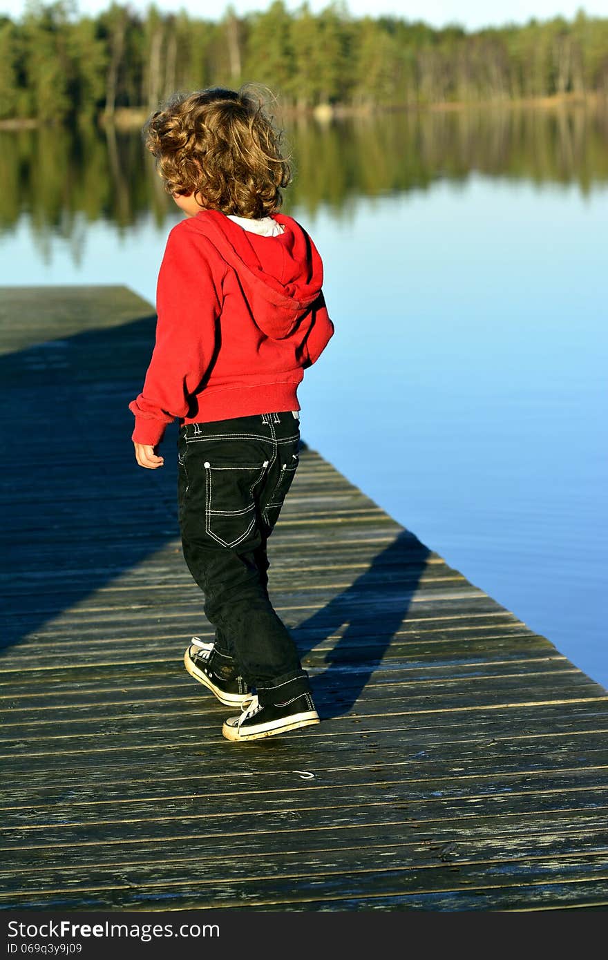 Kid playing in autumn sun by the lake. Kid playing in autumn sun by the lake